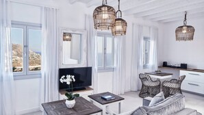 A modern living room with a sofa, a TV, wicker chairs, and a dining area with a table and chairs. - Villa Vassena - 1BD, Luxury villa, near beach Elia (C9HP+7QR Mikonos, Greece)