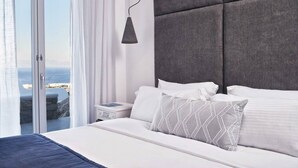 A modern bedroom with a large bed, a nightstand, a bedside lamp, and a view of the sea through a sliding glass door. - Villa Vassena - 1BD, Luxury villa, near beach Elia (C9HP+7QR Mikonos, Greece)