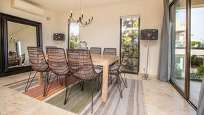 Ein Essbereich mit Holztisch, Korbstühlen, einer Chandelier und einem großen Spiegel.
