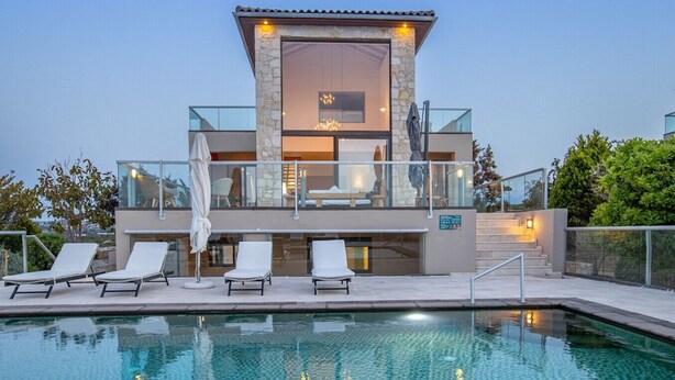 Ein modernes Haus mit Swimmingpool, Liegestühlen und einer gläsernen Veranda.