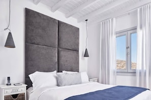 A modern bedroom with a large bed, a nightstand, a lamp, and a window with curtains.