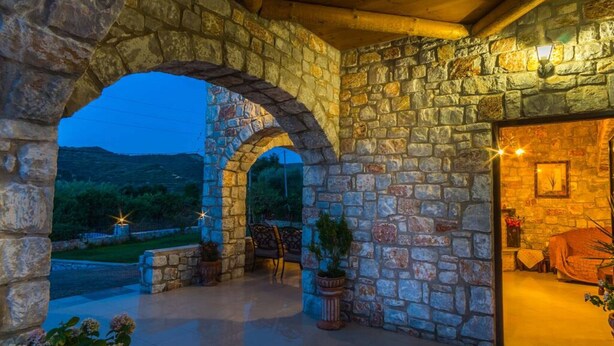 A stone archway leading to an outdoor seating area with potted plants and a view of the landscape. - Villa Vicina - In Platanias and 4min by the beach (GV2W+PVV Platanias, Greece)