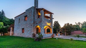 A stone house with a chimney, arched windows, and a wooden deck. - Villa Vicina - In Platanias and 4min by the beach (GV2W+PVV Platanias, Greece)
