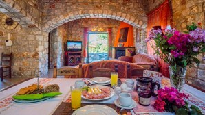 A stone-walled room with a dining table set for breakfast, including plates, cutlery, and a vase of flowers. - Villa Vicina - In Platanias and 4min by the beach (GV2W+PVV Platanias, Greece)