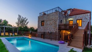 A stone building with a pool, wooden deck, and a staircase leading to a balcony. - Villa Vicina - In Platanias and 4min by the beach (GV2W+PVV Platanias, Greece)