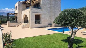 Un bâtiment en pierre de deux étages, doté d’une piscine, d’un patio couvert et d’une pelouse bien entretenue.