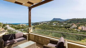 Un balcon doté de meubles en osier et offrant une vue dégagée sur un paysage côtier.