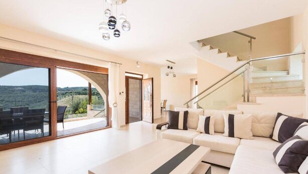 Un salon spacieux avec un grand canapé, une table basse et un escalier menant à l’étage supérieur.