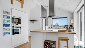 Una cocina moderna con armarios blancos, una isla de madera y vistas al exterior.