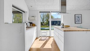 Una cocina moderna con una isla grande, vistas al jardín trasero y un comedor.