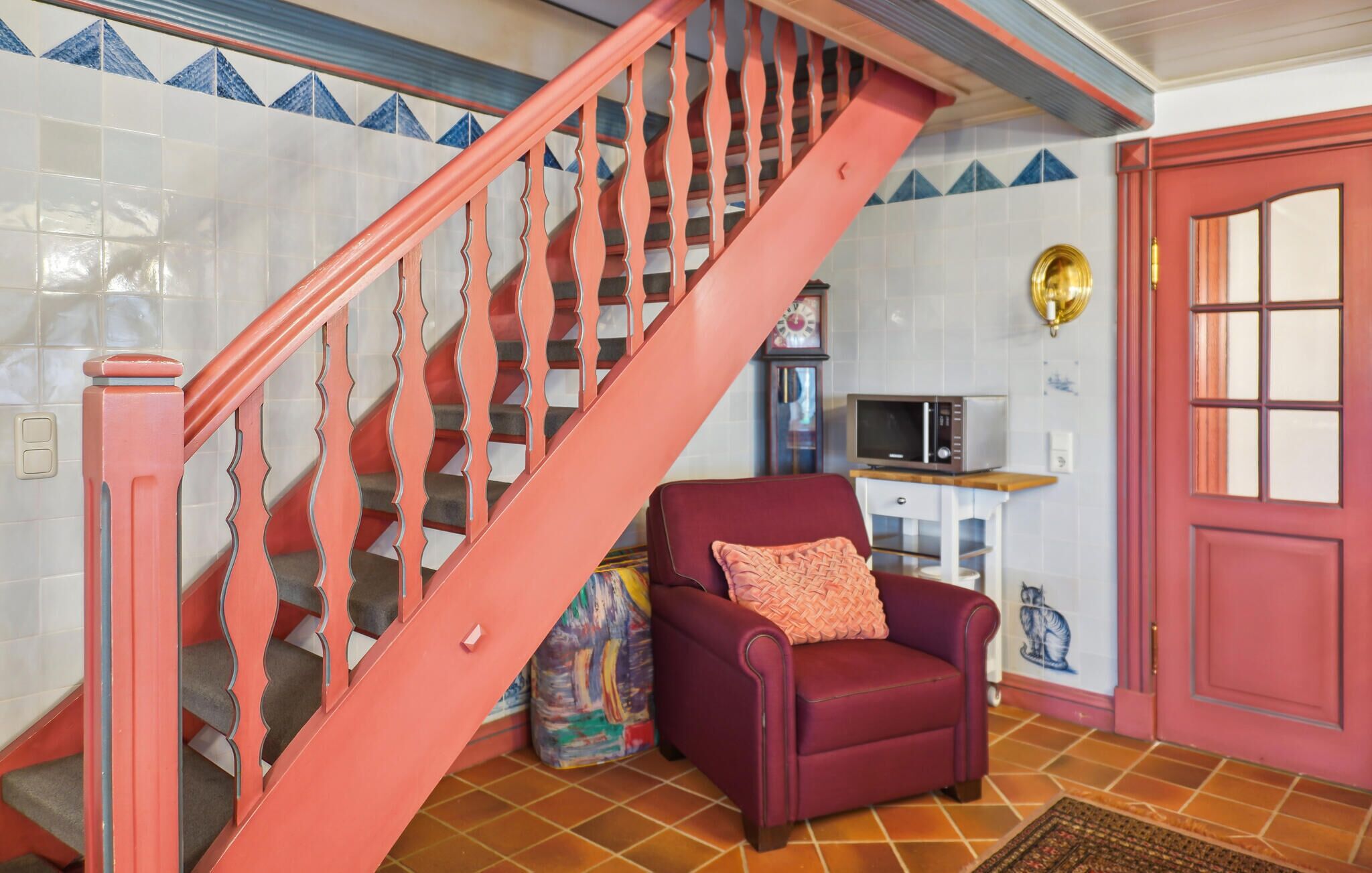 A staircase with a red handrail and a red door.