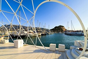 Un puerto deportivo con barcos amarrados, cielo despejado y montañas al fondo.