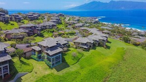 Um bairro residencial com casas, um campo de golfe e vista para o oceano e montanhas.