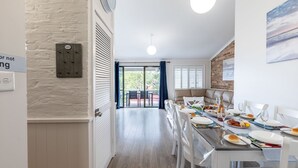 Una cuina moderna amb zona de menjador, que inclou un forn de sobre i una taula de dinar preparada per a una estada, i vista a la terrassa exterior.