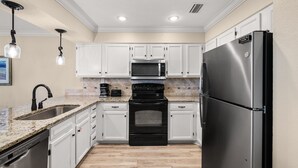 A kitchen with white cabinets, a black stove, a stainless steel refrigerator, and a granite countertop. - 4C, Meet Me at The Gulf (Miramar Beach)