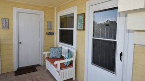 A porch with a white bench, a door, and a window with a 'Living Life the Beach' sign. - 7G, Emerald Escape (Destin)