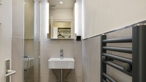 Une salle de bain moderne avec une douche à parois de verre, un lavabo blanc et un porte-serviettes.