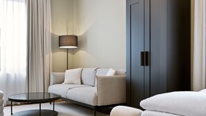 Une chambre d’hôtel moderne avec un canapé, une table basse ronde, une lampe et une armoire.