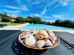 A wicker basket filled with seashells on a poolside lounge chair. - Villa Giada (Olbia)