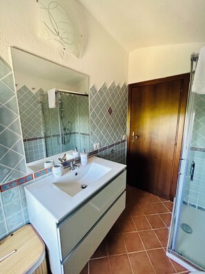 Een badkamer met een grote spiegel, een wit wastafelmeubel en een douchehoek.