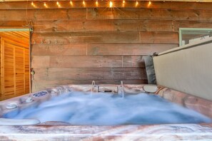 Un bain à remous avec un mur en bois en arrière-plan, une porte et une fenêtre.