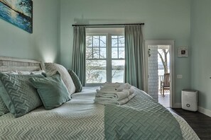 Une chambre avec un grand lit, une vue par la fenêtre et une porte donnant sur un balcon.