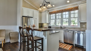 A kitchen with white cabinetry, a central island, stainless steel appliances, and a window with a view. - A Lake Blue Ridge Cottage | Morganton, GA (Morgantown)