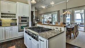 A spacious kitchen with white cabinetry, a large island, and a dining area with a view. - A Lake Blue Ridge Cottage | Morganton, GA (Morgantown)