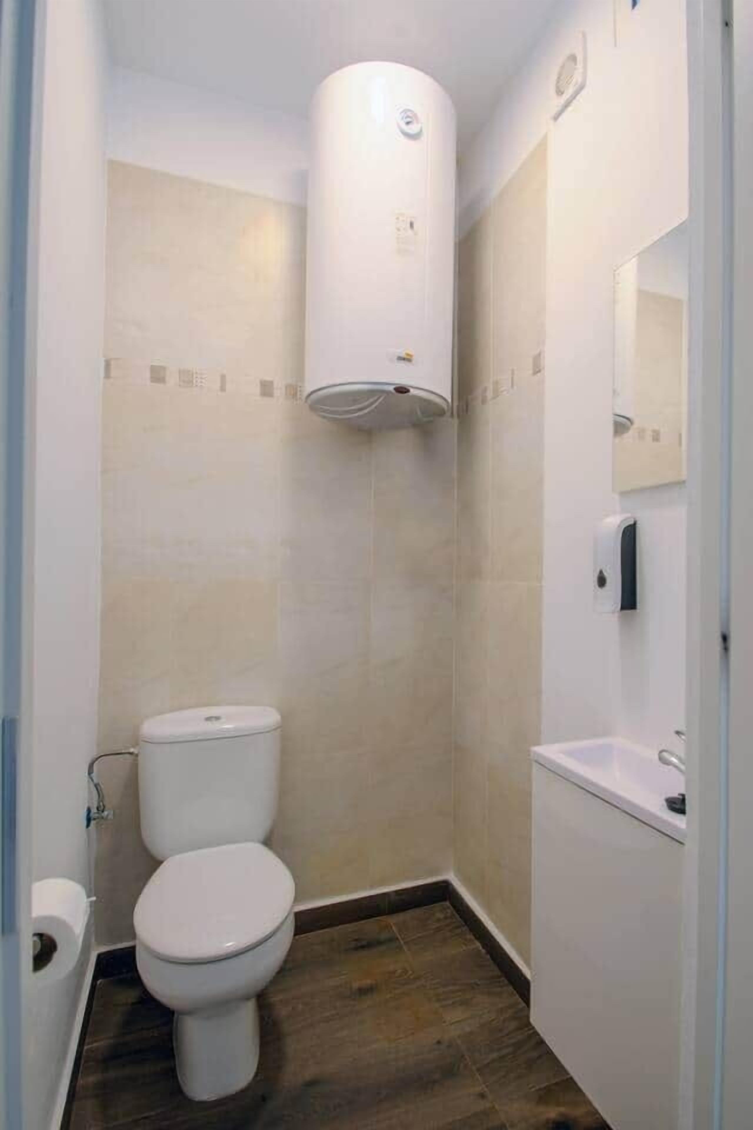 A small, modern bathroom with a toilet, a sink, and a toilet paper holder.