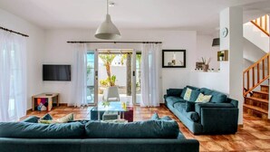 A modern living room with a sofa, a coffee table, a TV, and a staircase. - Villa Fedelian 1 with garden and heated pool (Playa Blanca)