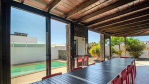 A covered outdoor dining area with a pool in the background. - Villa Fedelian 1 with garden and heated pool (Playa Blanca)
