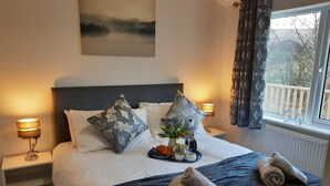 A neatly made bed with pillows, a tray of fruits and a coffee maker, and towels on a dark blue quilt. - Luxury 3 bedroom, pet-friendly lodge on the side of a beautiful fishing lake. (Clitheroe)