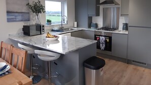 A modern kitchen with a marble island, stainless steel appliances, and a view of the outdoors. - Luxury 3 bedroom, pet-friendly lodge on the side of a beautiful fishing lake. (Clitheroe)