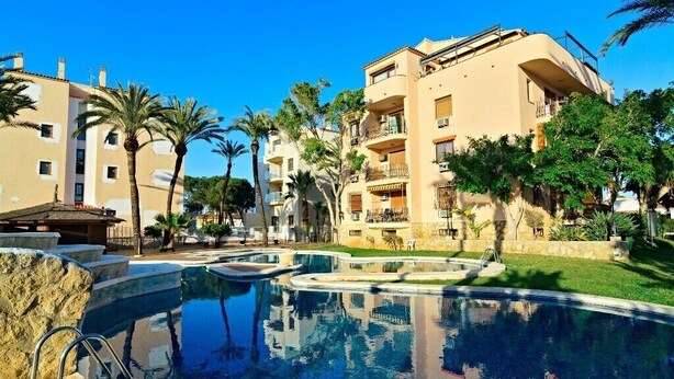 Un resort con piscina, palmeras y edificios de varios pisos.