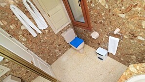 Un baño con inodoro, lavamanos, espejo y toallero.