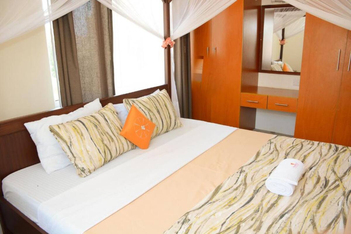 A hotel room with a bed, a bedside table, a mirror, and a wardrobe.