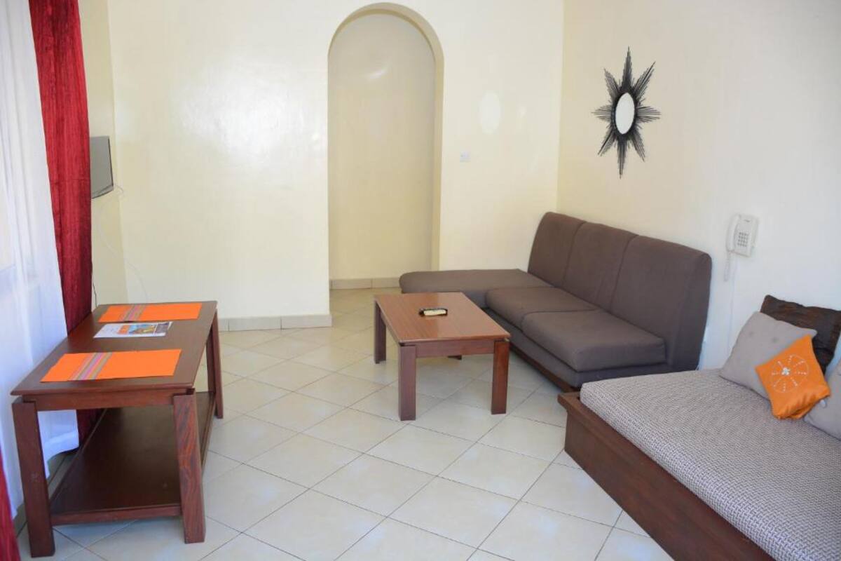 A living room with a sofa, two wooden tables, a red curtain, and a wall-mounted star decoration.