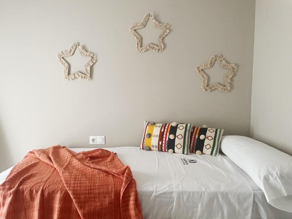 A bedroom with a bed, a blanket, and three star-shaped wall decorations.