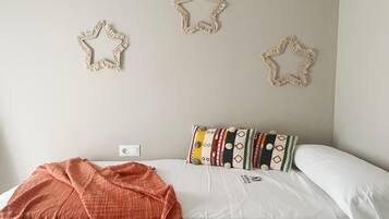 A bedroom with a bed, a blanket, and three star-shaped wall decorations.