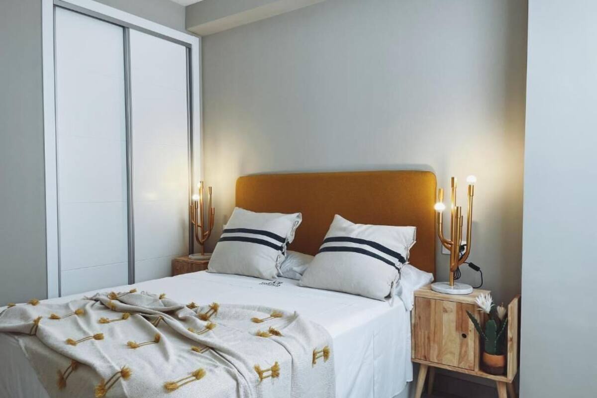 Un dormitorio con cama, mesitas de noche, un aparador, un armario de madera y una planta en maceta.