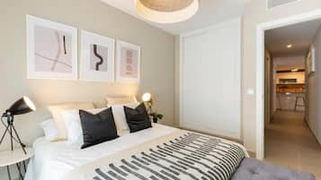 A modern bedroom with a large bed, bedside lamps, and artwork on the wall.