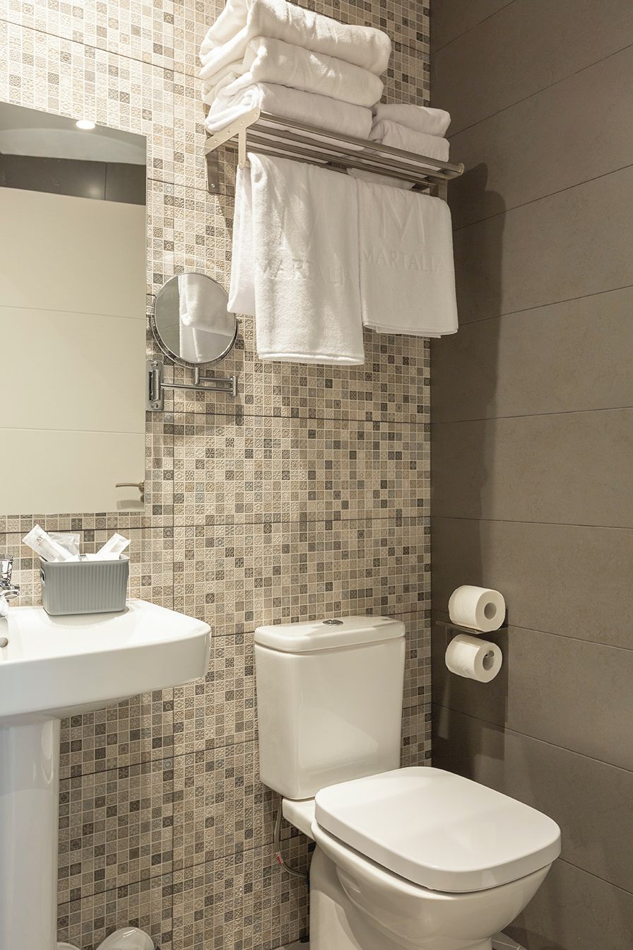 Egy fürdőszoba, amelyben WC, mosdókagyló és törölközőtartó található.