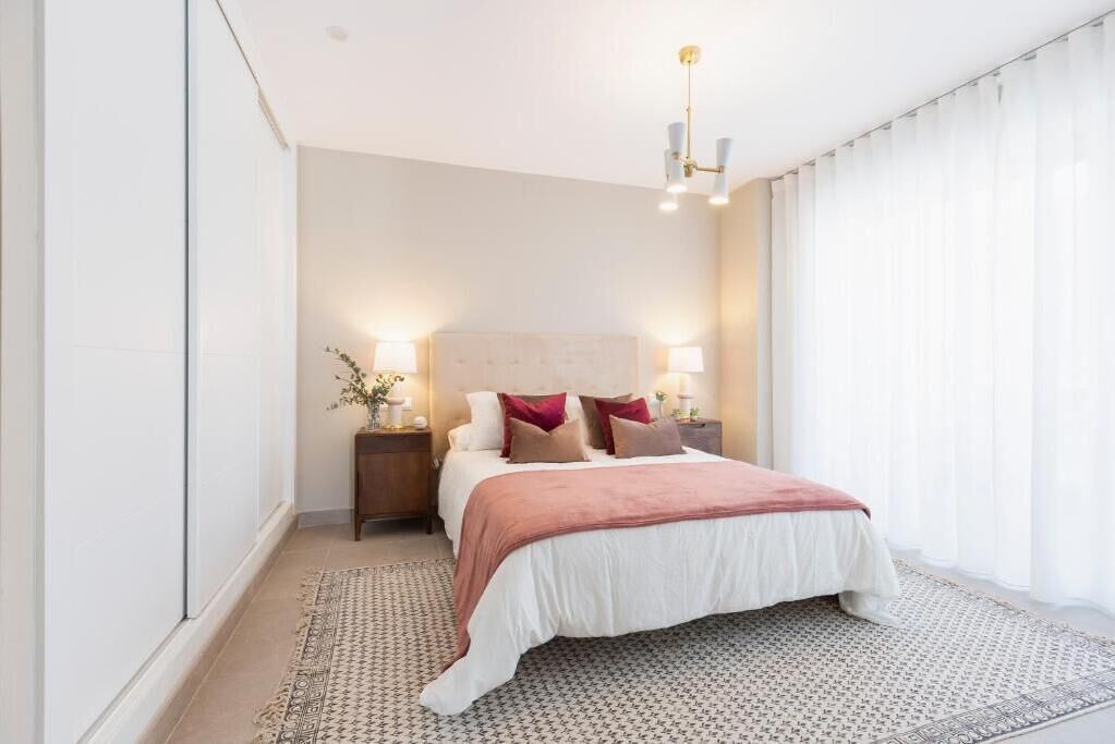 A modern bedroom with a large bed, bedside lamps, and a patterned rug.