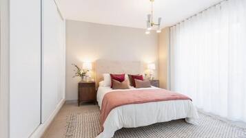 A modern bedroom with a large bed, bedside lamps, and a patterned rug.