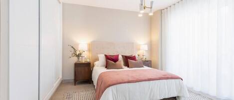 A modern bedroom with a large bed, bedside lamps, and a patterned rug.