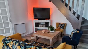 Una sala de estar con un sofá, una mesa de centro, un televisor y una escalera.