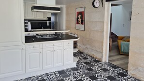 Una cocina moderna con armarios blancos, piso con estampado blanco y negro, y un reloj en la pared.
