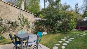 Un patio con una mesa, sillas, una planta en maceta y un muro de piedra.