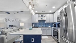 Een moderne keuken met een centraal eiland, roestvrijstalen apparatuur en een blauwe achterwand.