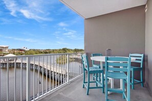 Un balcon donnant sur un plan d’eau et un pont, avec une table et des chaises.